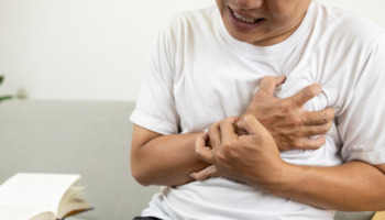 A man clutches his chest. chest pains can be a potential side effect of synthetic marijuana