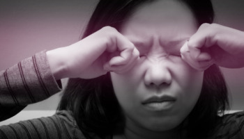 A woman rubs her eyes whole suffering from a headache or disorientation.