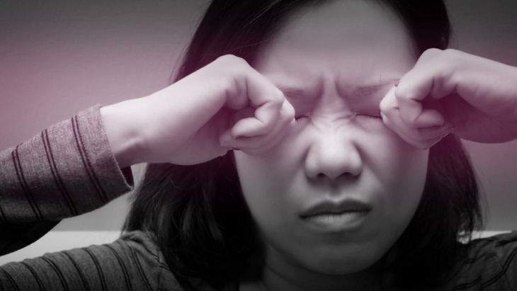 A woman rubs her eyes whole suffering from a headache or disorientation.