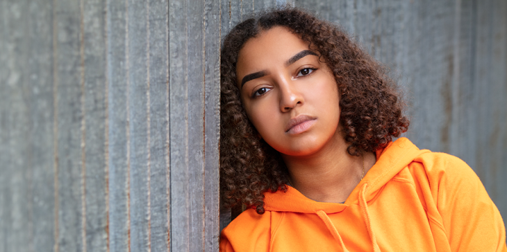 Girl leaning head against wall thinking why is teenage mental illness soaring