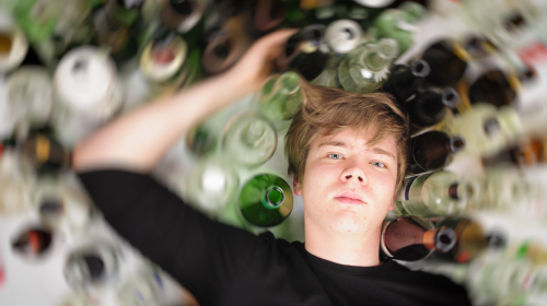 04 alcohol bottles surrounding young male