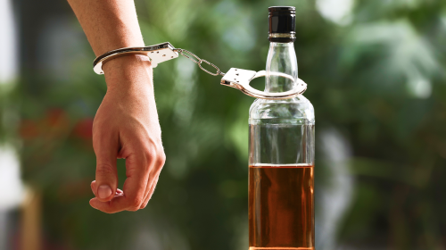 man cuffed to alcohol bottle