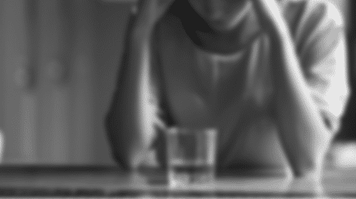 woman looking down at glass of alcohol