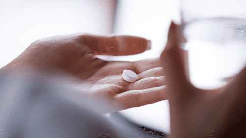persons hand holding medicine tablet