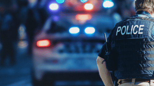 police officer standing behind squad car