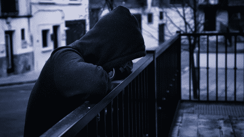 strange person in hoodie leaning on fence