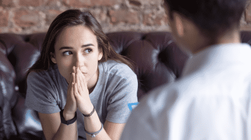 woman thinking with hands in front of mouth