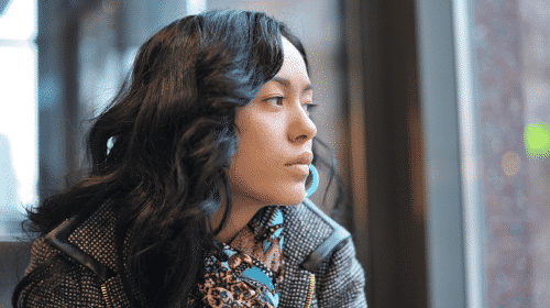 young woman staring out of window