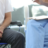 Man sitting in a wheelchair next to his doctor