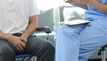 Man sitting in a wheelchair next to his doctor