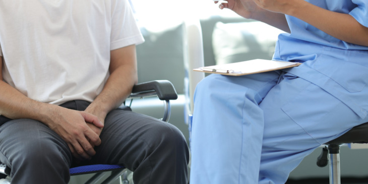 Man sitting in a wheelchair next to his doctor