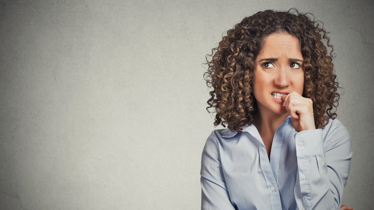 A woman anxiously bites her finger