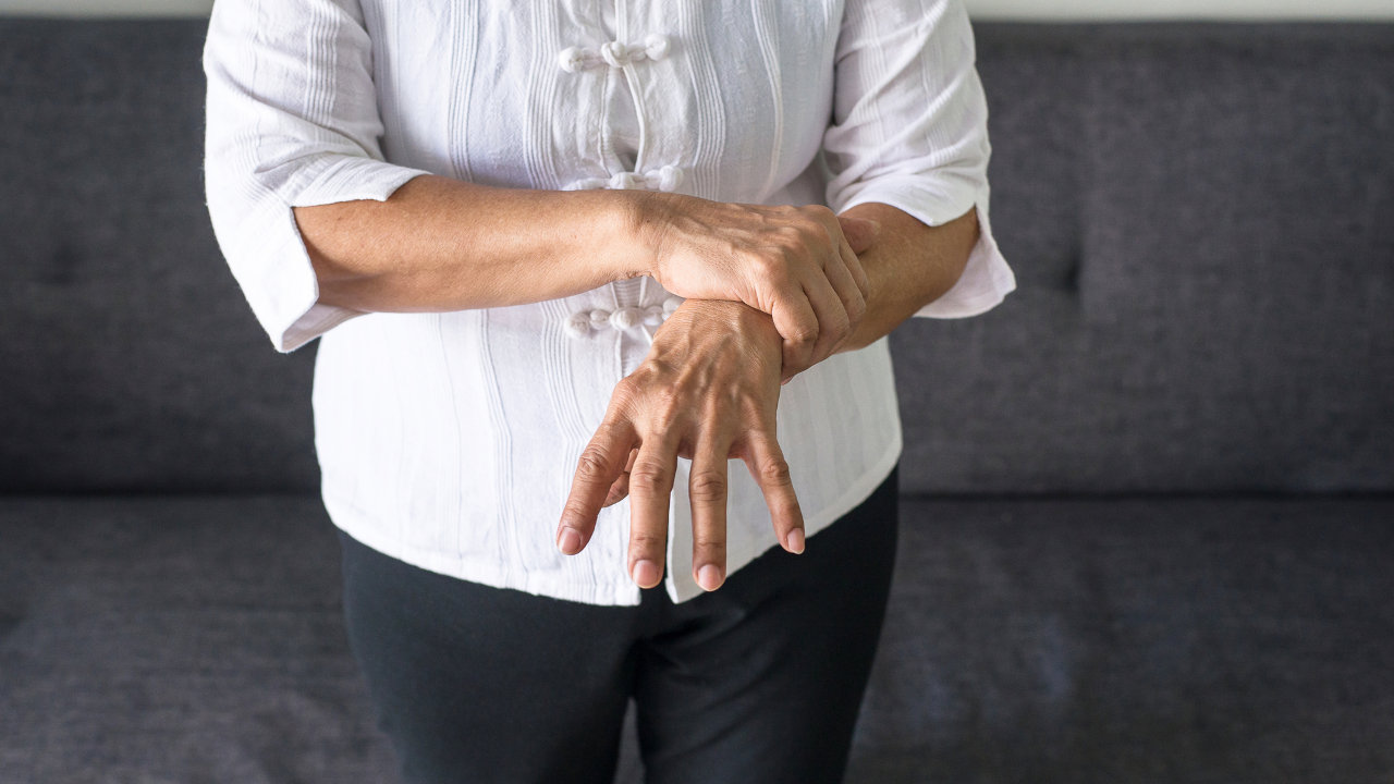 A woman grips her wrist as she suffers from hand tremors