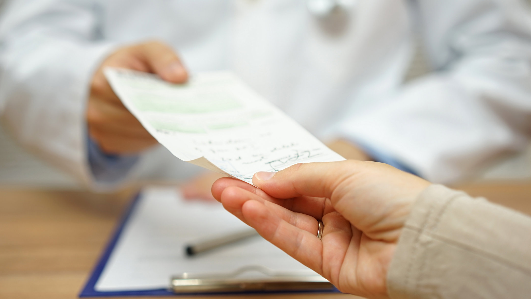 A doctor hands a written prescription to a patient, such as a prescription for methadone to treat opioid addiction