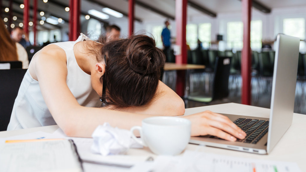 A woman falling asleep at her desk, which could be a possible sign of lunesta overdose