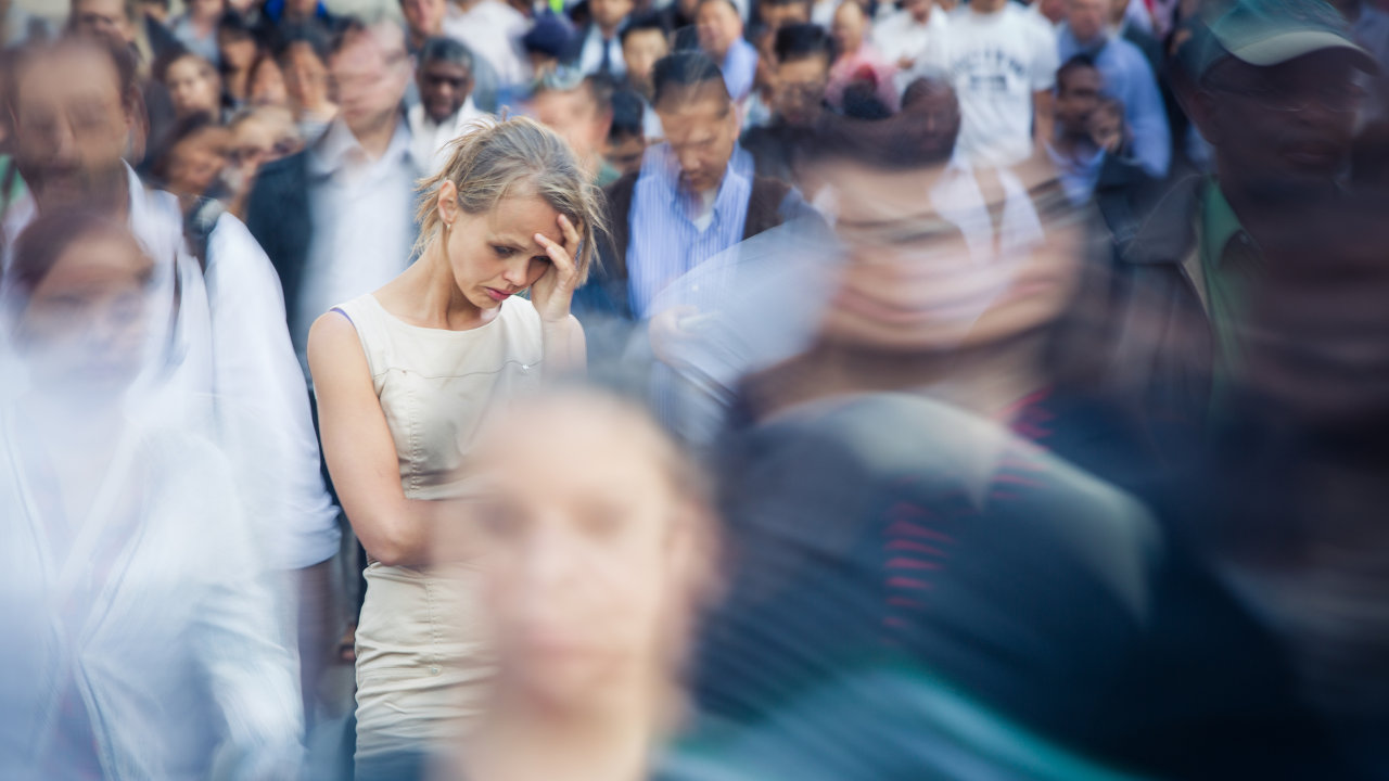 A woman anxiously clutches her head in the middle of a crowd, suffering from symptoms of ecstasy withdrawal
