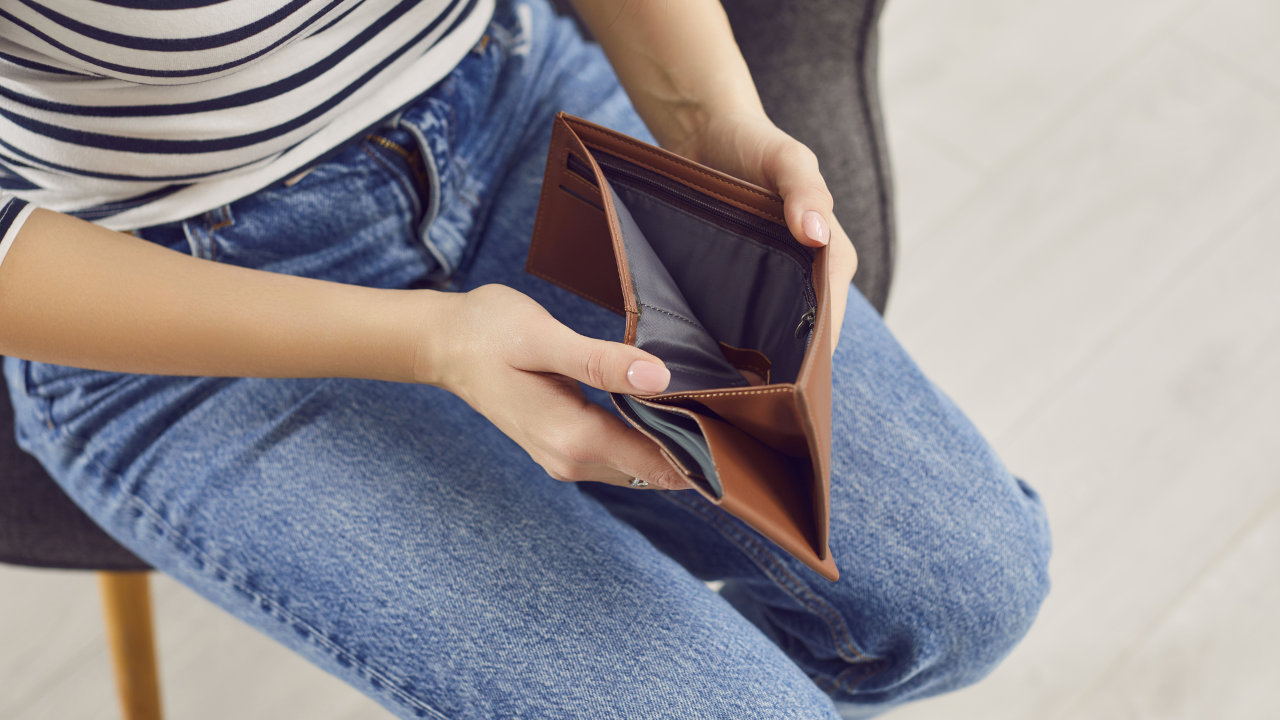 A person opens their wallet to see no money inside.