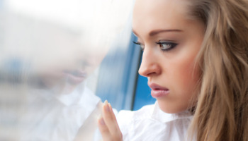 An anxious or depressed looking woman looks out her window