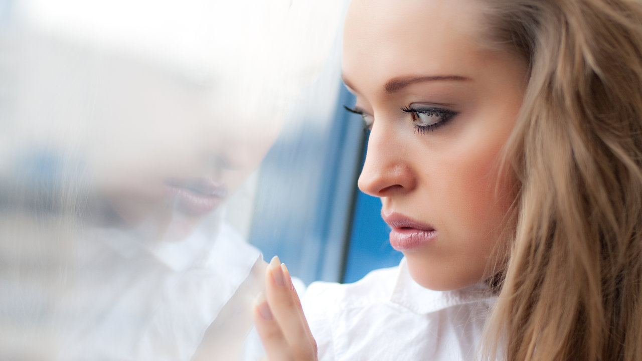 An anxious or depressed looking woman looks out her window