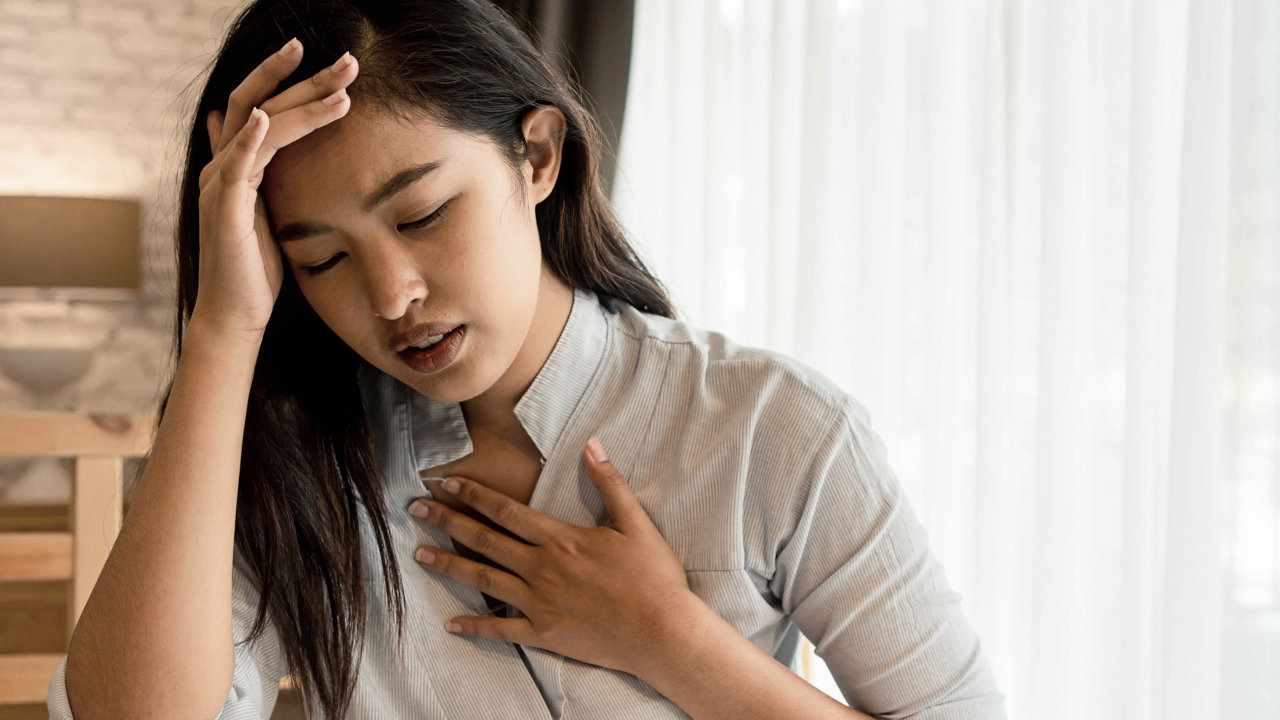 A woman clutches her head and chest in distress