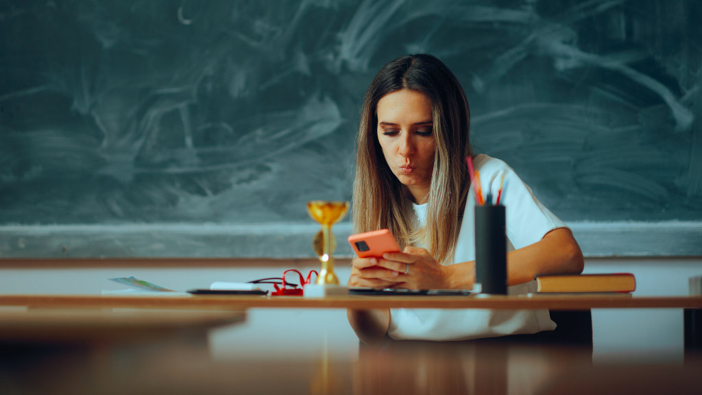 A woman looks at her phone while sitting at a table. Excessive internet use can be a sign of internet addiction