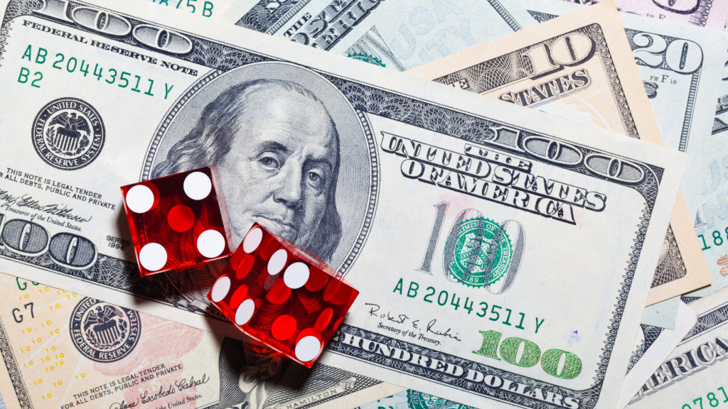 A pair of dice sitting atop a 100 dollar bill, suggesting a gambling addiction. Inpatient gambling treatment centers can help manage problem gambling.
