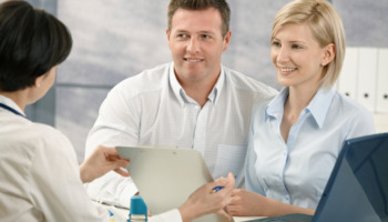 A doctor speaking with a patient and their partner at an outpatient rehab clinic