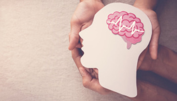 A person holding a graphic of a head with a brain. Learn more about ADHD and addiction here.