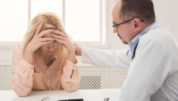 A distressed woman speaking with a doctor. Learn more about common addiction relapse triggers and how to manage them here.