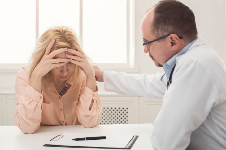 A distressed woman speaking with a doctor. Learn more about common addiction relapse triggers and how to manage them here.
