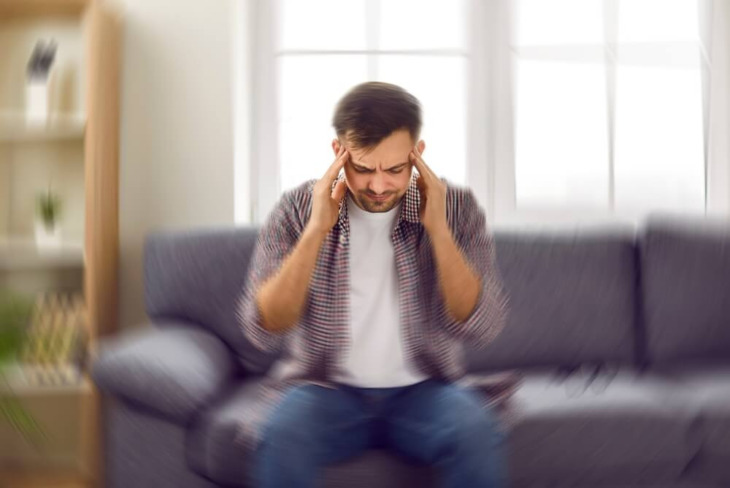 A man sitting on a couch grips his head. Learn more about gabapentin withdrawal here.
