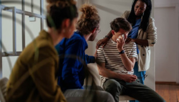 People speaking with someone at a support group. Learn more about how to talk to someone who doesn't think they have a problem or addiction, here.
