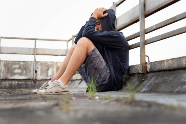 A lonely man sits on the ground, clutching his head. Learn more about how to talk to an addict and when substance use becomes a substance use disorder, here.