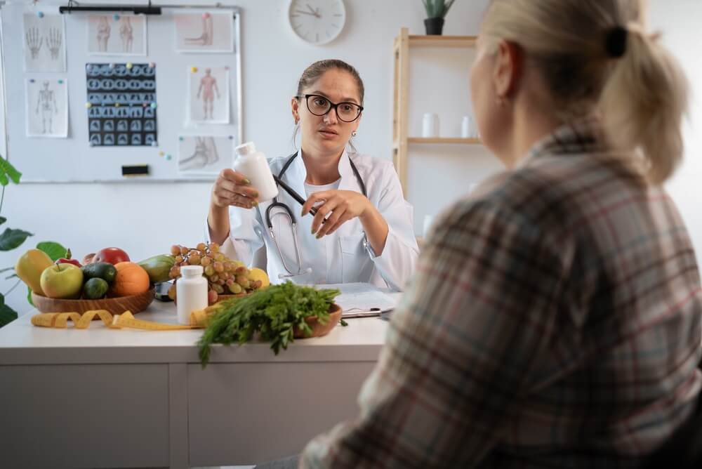 A nutritionist speaks with a patient while holding a bottle of vitamins. Learn more about addiction detox here.
