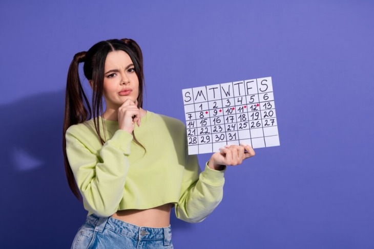 A woman with a curious look holds a calendar. learn more about how long rehab is, here.