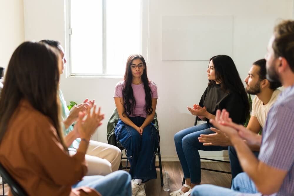 People surround a person during a support meeting