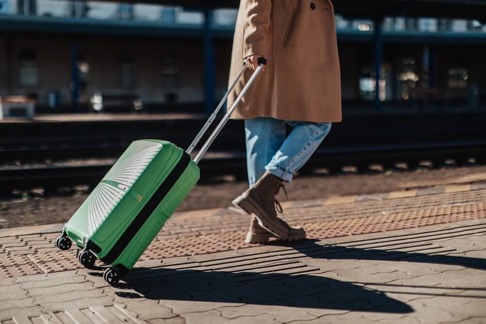 A woman with a roller bag. Learn more if you should travel for treatment and detox here.