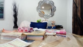 Interior office space with wooden desk, decorative mirror, desk accessories, and organizational items on surface