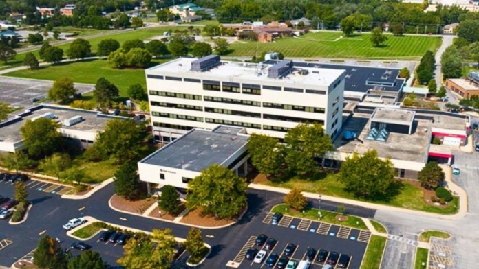 Exterior aerial view of multi-building medical facility campus with parking lots, landscaping, and surrounding area