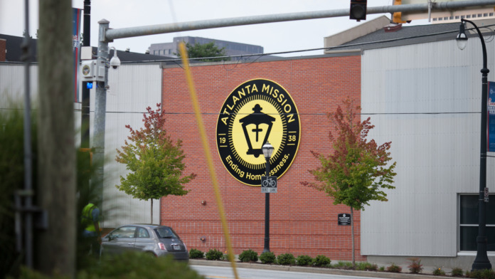 Exterior view of brick building with Atlanta Mission logo, visitor parking area, and street-level entrance