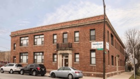 Exterior corner view of red brick treatment facility with multiple windows, parked vehicles, and street signage visible