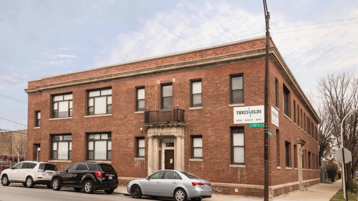 Exterior corner view of red brick treatment facility with multiple windows, parked vehicles, and street signage visible