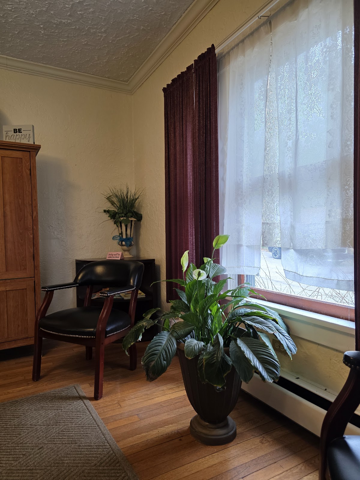 Interior lounge area with fireplace, comfortable seating chairs, potted plants, and large windows with natural lighting