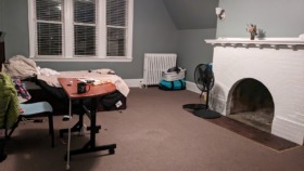 Interior common room with fireplace, large windows with blinds, radiator heater, storage furniture, and open floor space