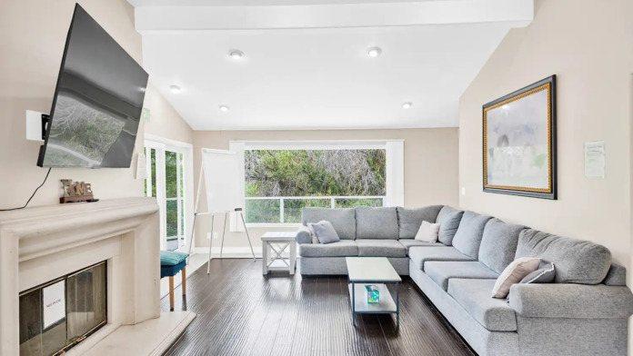 Interior common area featuring sectional sofa, fireplace, wall-mounted television, and sliding glass doors to outdoor views