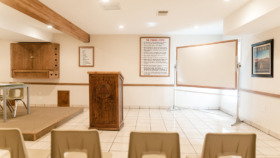 Interior group room with light wooden furnishings, recovery program materials on walls, tile flooring, and open space for group activities