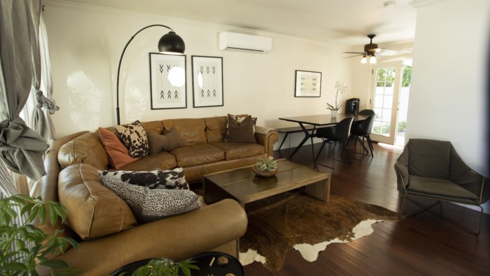 Interior living space with cognac leather sectional sofa, wooden coffee table, modern furnishings, large windows with natural light