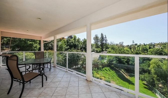 Exterior covered patio with patio furniture and expansive views of manicured grounds and natural landscape