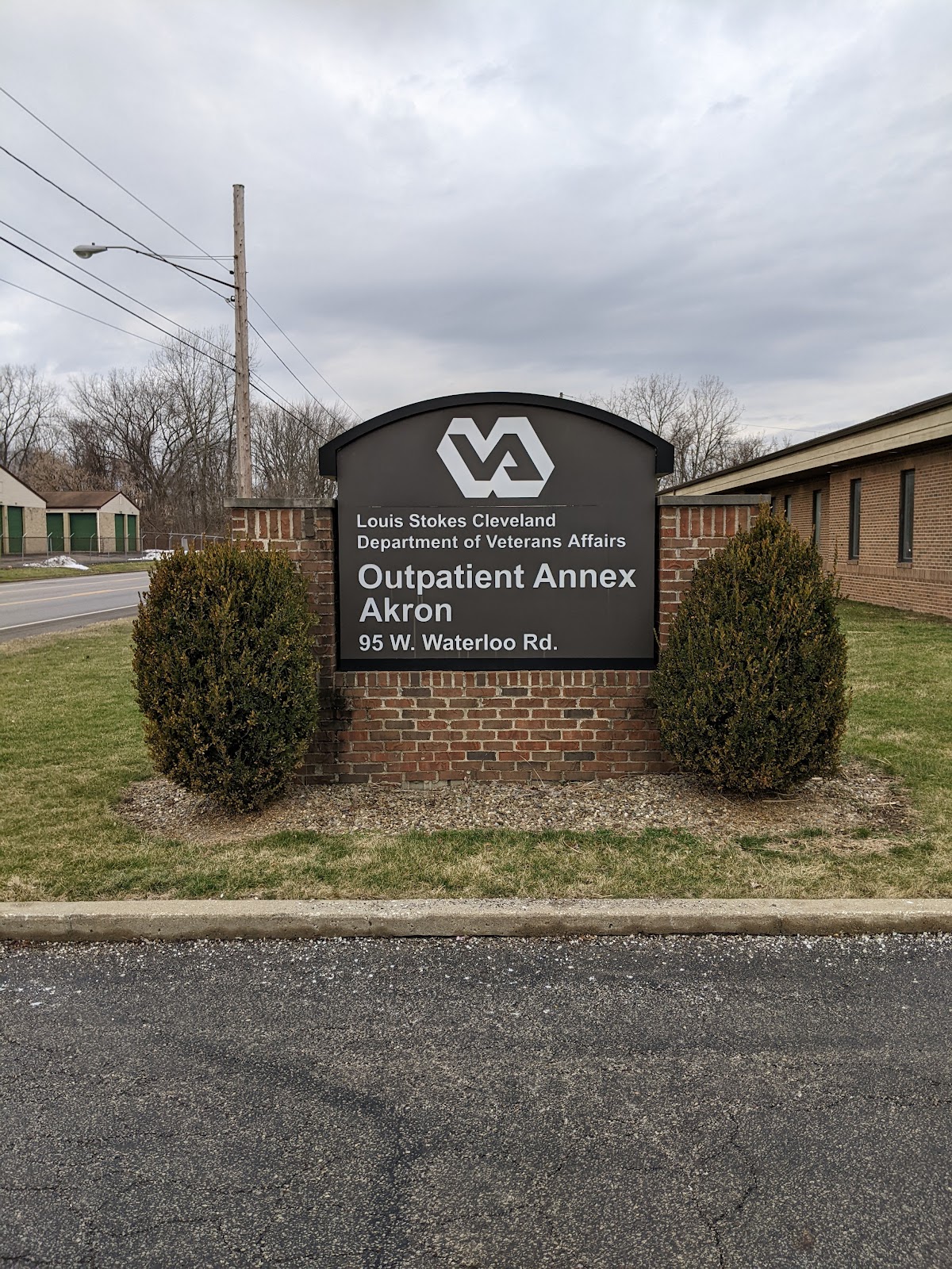 Exterior sign for Louis Stokes Cleveland Department of Veterans Affairs Outpatient Annex Akron at 95 W. Waterloo Rd with landscaping