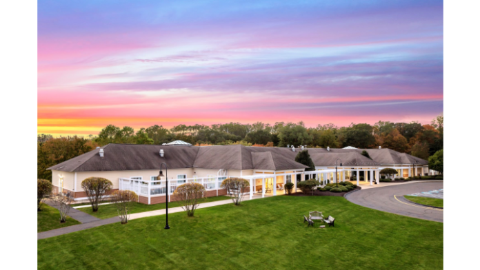Exterior view of single-story behavioral health facility with white trim, columned entrance, and manicured grounds at dusk